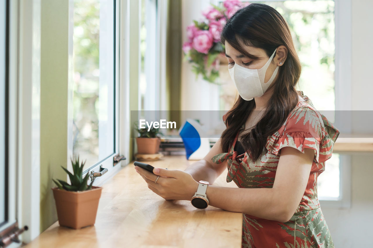 Young woman wearing mask using mobile phone