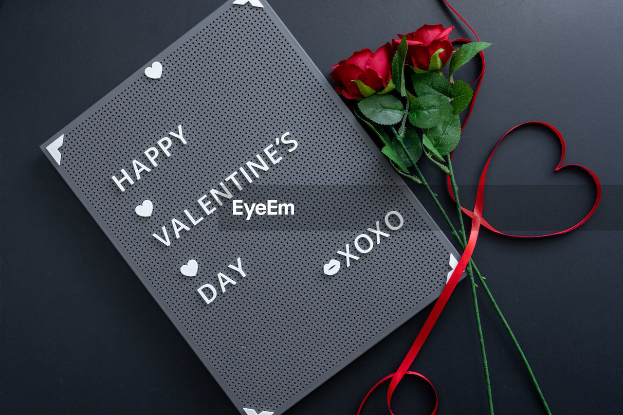 Beautiful valentine's day background with red hearts and roses on black banner background.