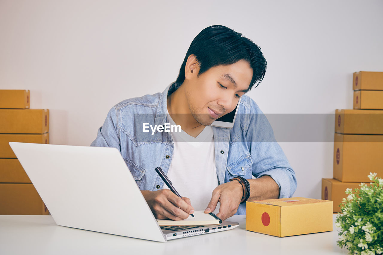 MAN LOOKING AT CAMERA WHILE SITTING ON TABLE