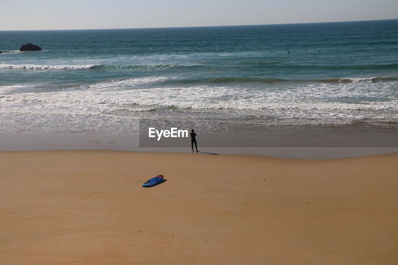 Mid distance of man standing on shore against sea at beach