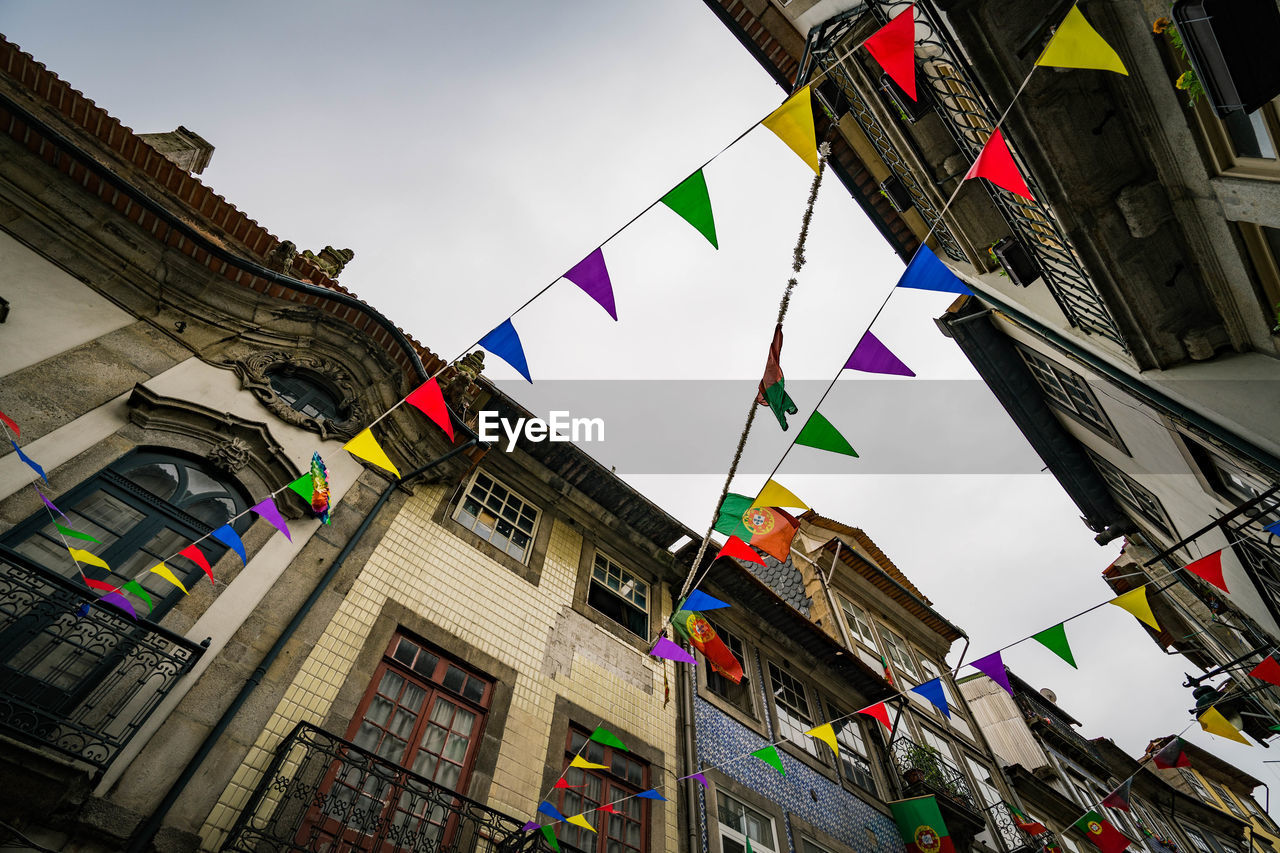 LOW ANGLE VIEW OF FLAGS HANGING AGAINST BUILDINGS