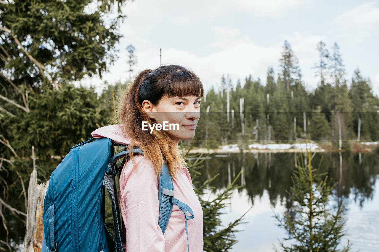 portrait of smiling woman standing against lake