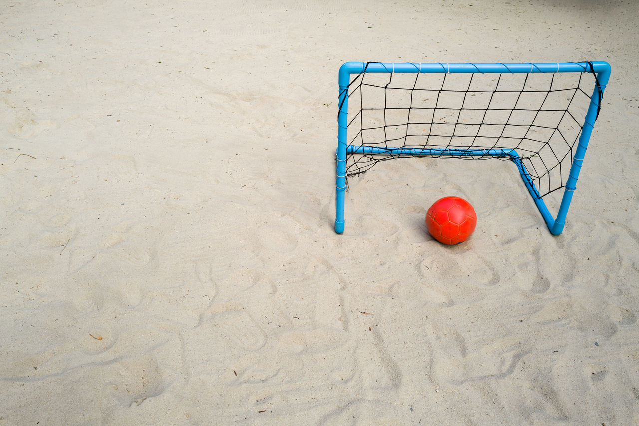 Blue goal with an orange ball on the sand