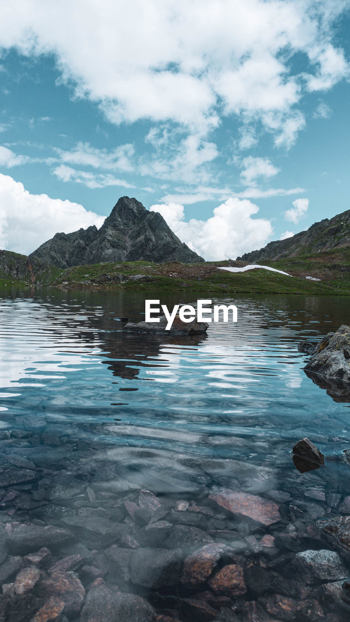 SCENIC VIEW OF LAKE BY MOUNTAIN AGAINST SKY