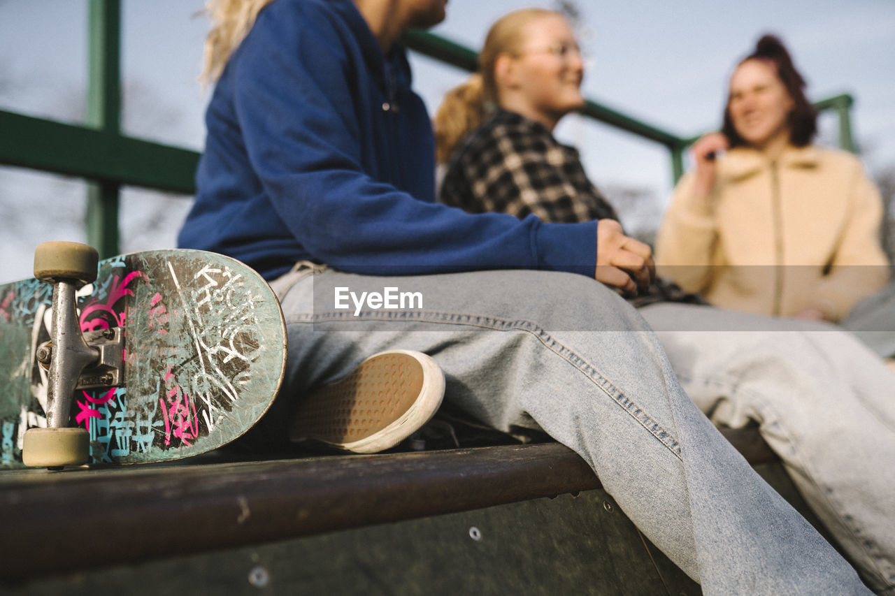 Teenage girls with skateboard sitting in skatepark