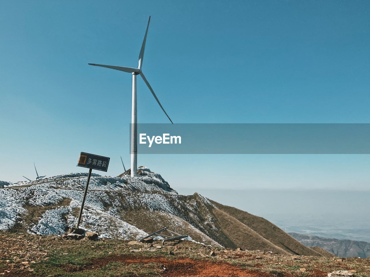 Wind turbines on landscape against clear blue sky