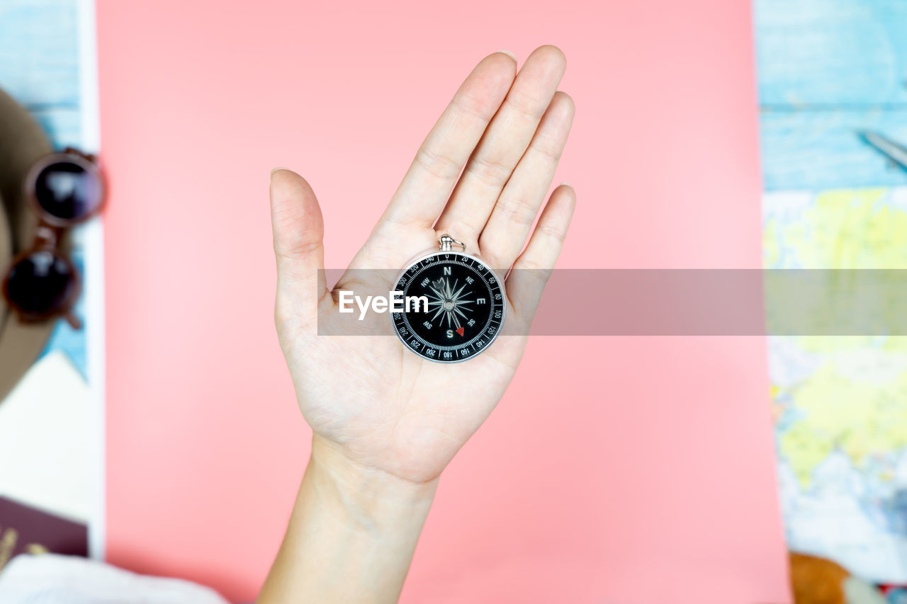 CLOSE-UP OF HUMAN HAND HOLDING CLOCK