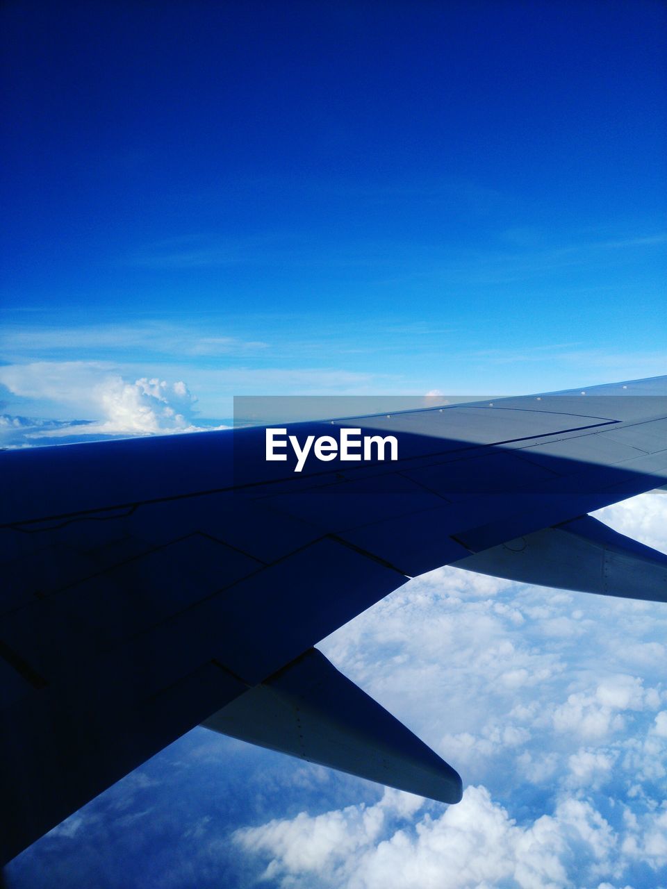 AIRPLANE WING FLYING OVER CLOUDS