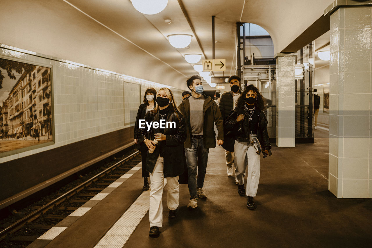 Young friends walking at subway station during pandemic