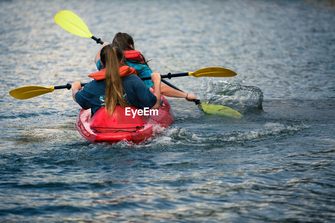 Rear view of girls kayaking in sea