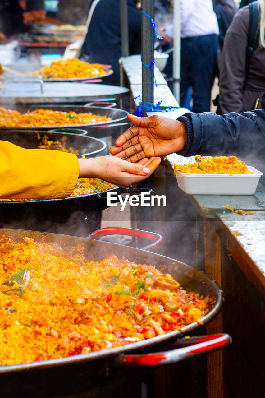 Hands meeting for a money exchange at an outdoor  market in london with street food including paella 