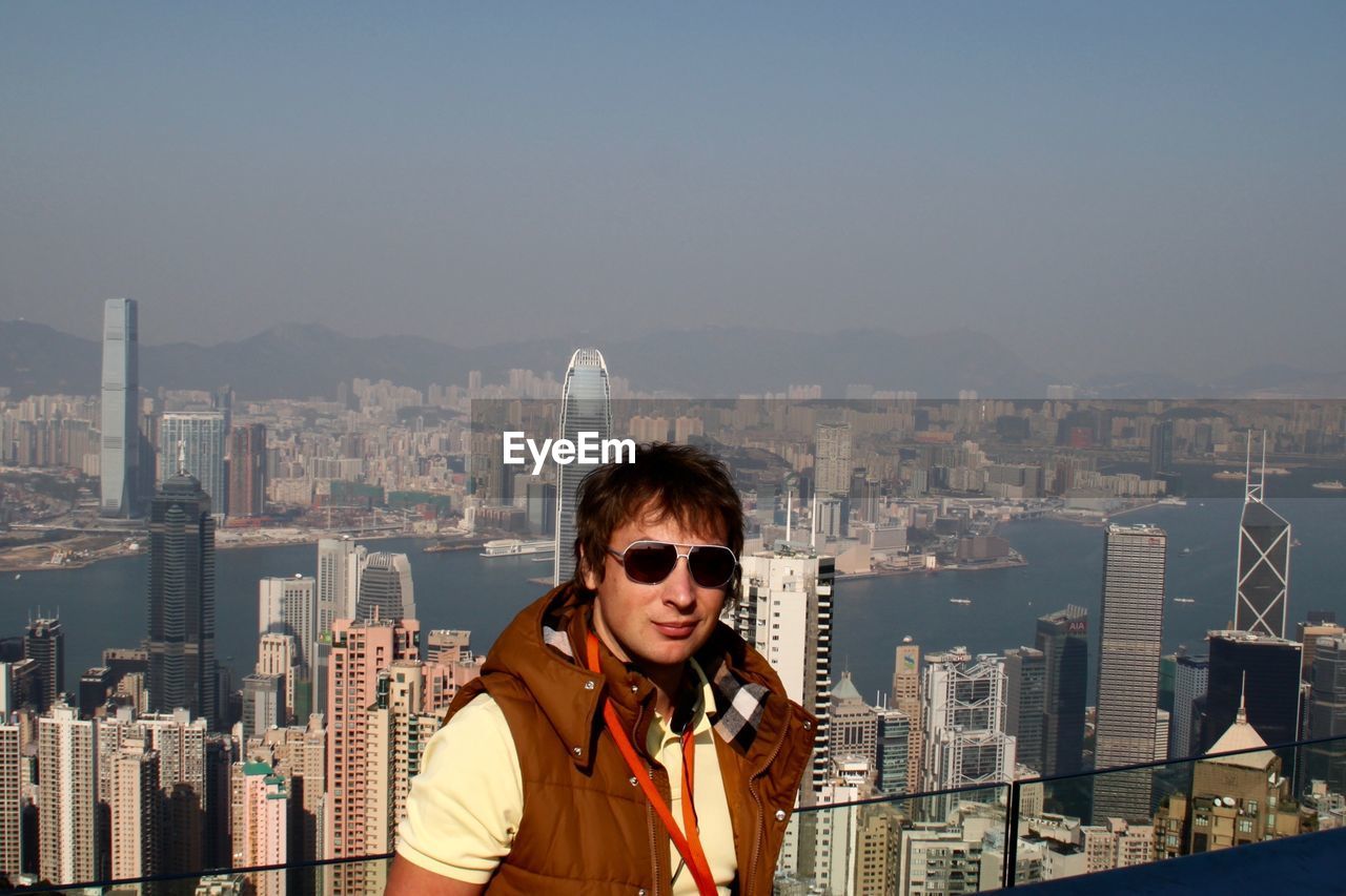 Young man against modern buildings at victoria harbour in city