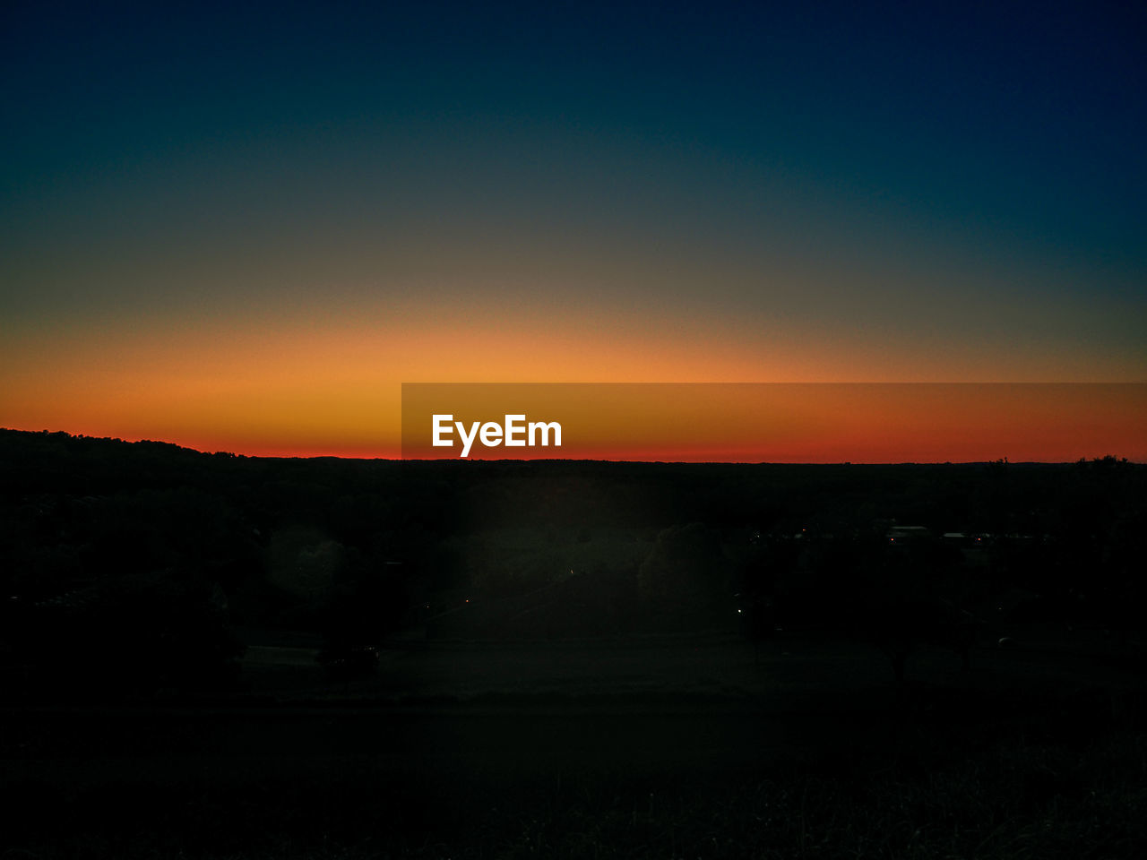SCENIC VIEW OF SILHOUETTE FIELD AGAINST ORANGE SKY