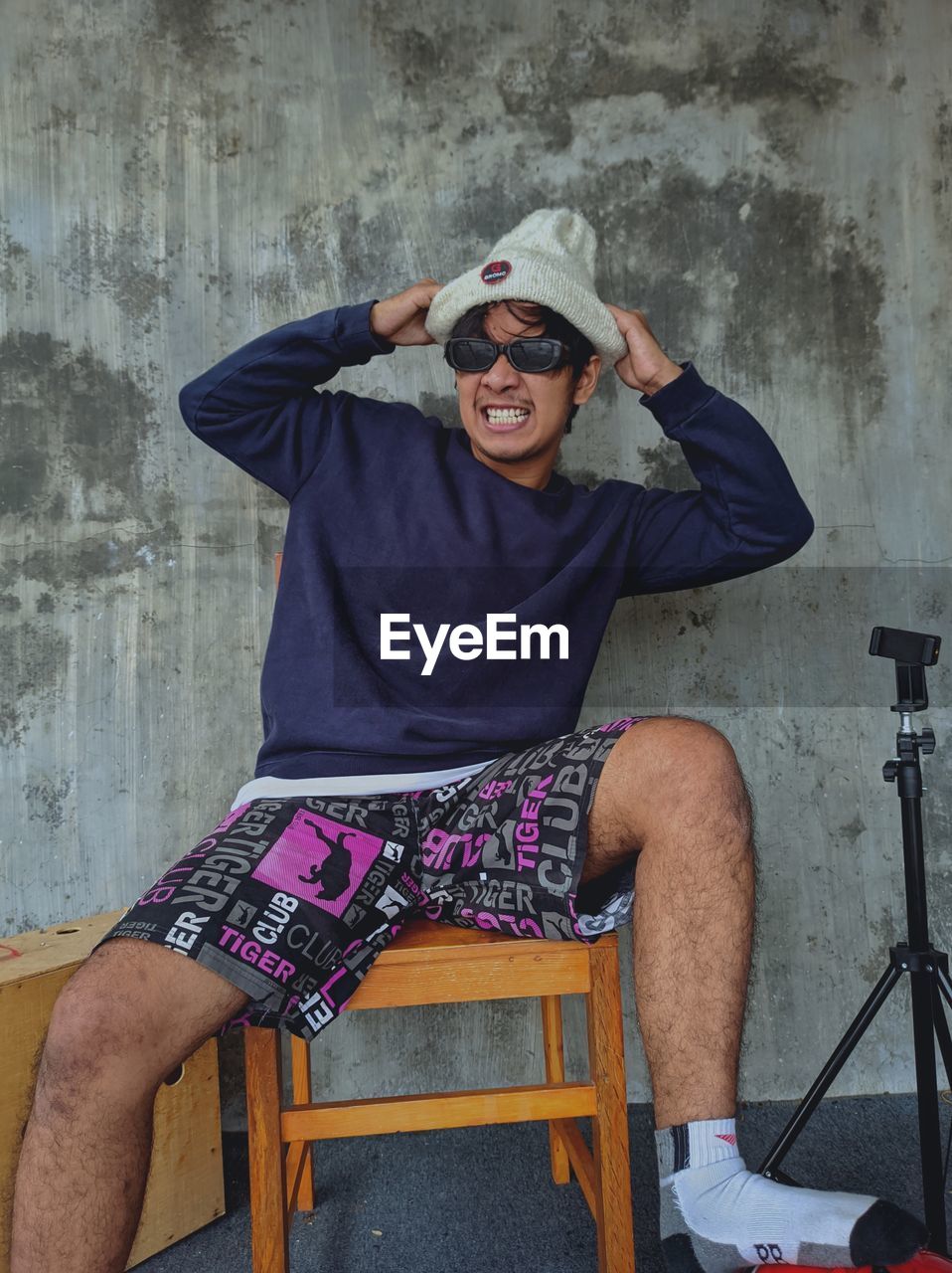 Frustrated man sitting on chair against wall