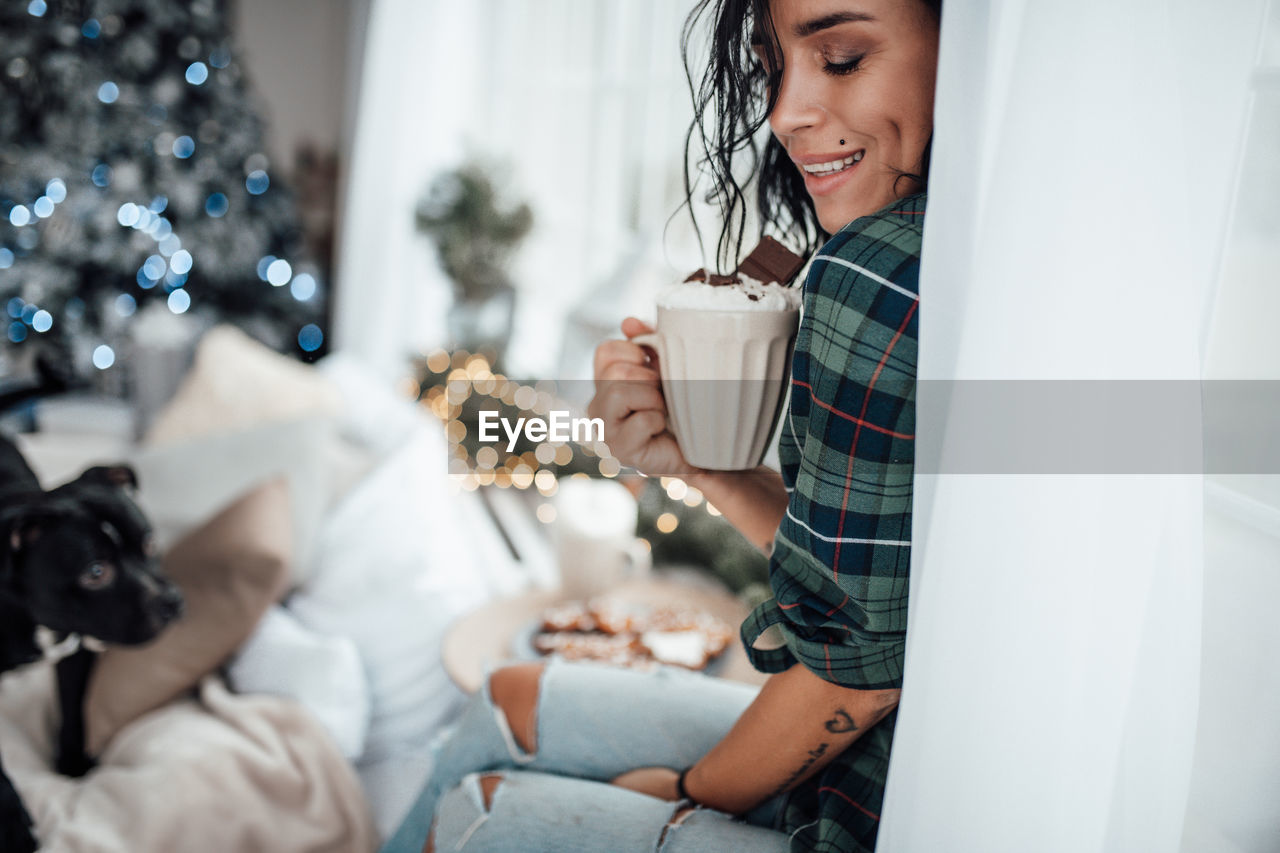 Smiling woman holding hot chocolate while sitting at home