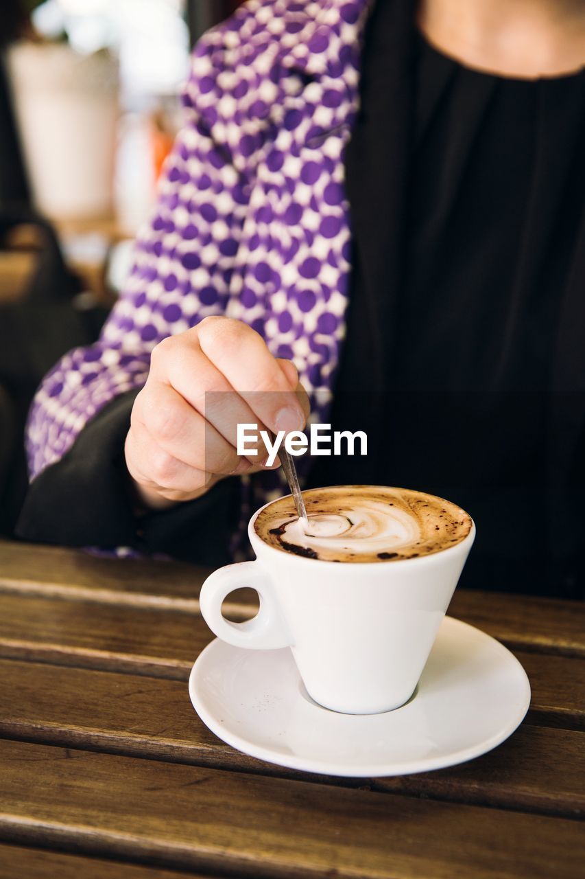 COFFEE CUP ON TABLE AGAINST CAFE