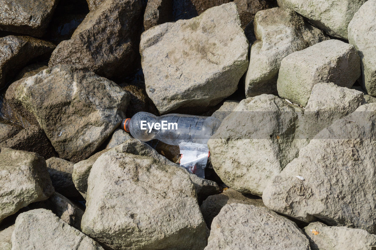 High angle view of empty bottle on rocks