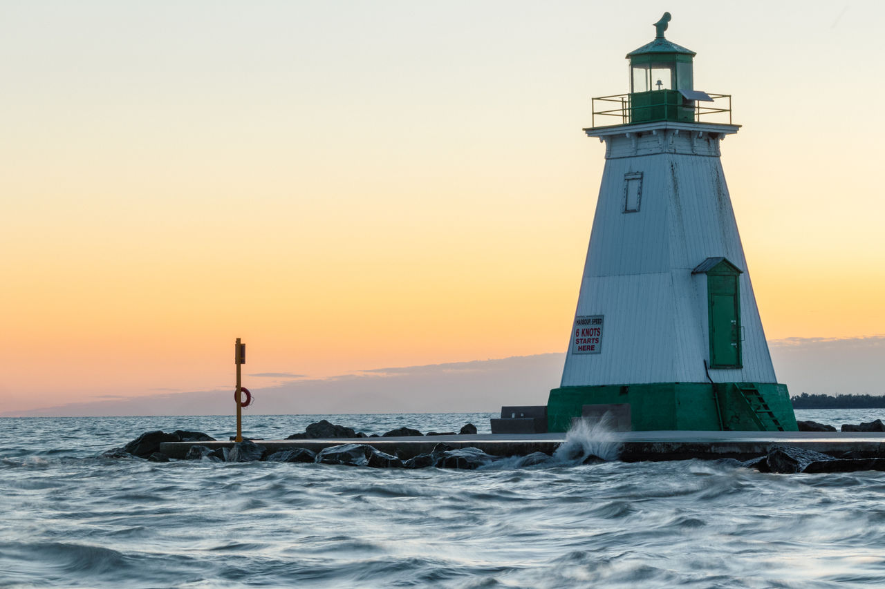 lighthouse, sea, guidance, water, tower, sky, sunset, architecture, built structure, ocean, building exterior, building, security, nature, beach, protection, travel destinations, travel, land, coast, nautical vessel, beauty in nature, horizon over water, scenics - nature, coastline, motion, horizon, wave, transportation, outdoors, clear sky, orange color, no people, silhouette, environment, tranquility, dusk, tranquil scene, idyllic, nautical equipment, vehicle, tourism, sunlight