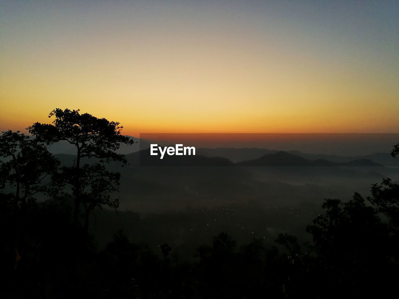 SILHOUETTE TREES AND MOUNTAINS AGAINST SKY DURING SUNSET