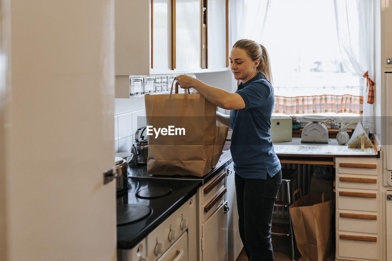 Female caregiver keeping bags on kitchen counter at home