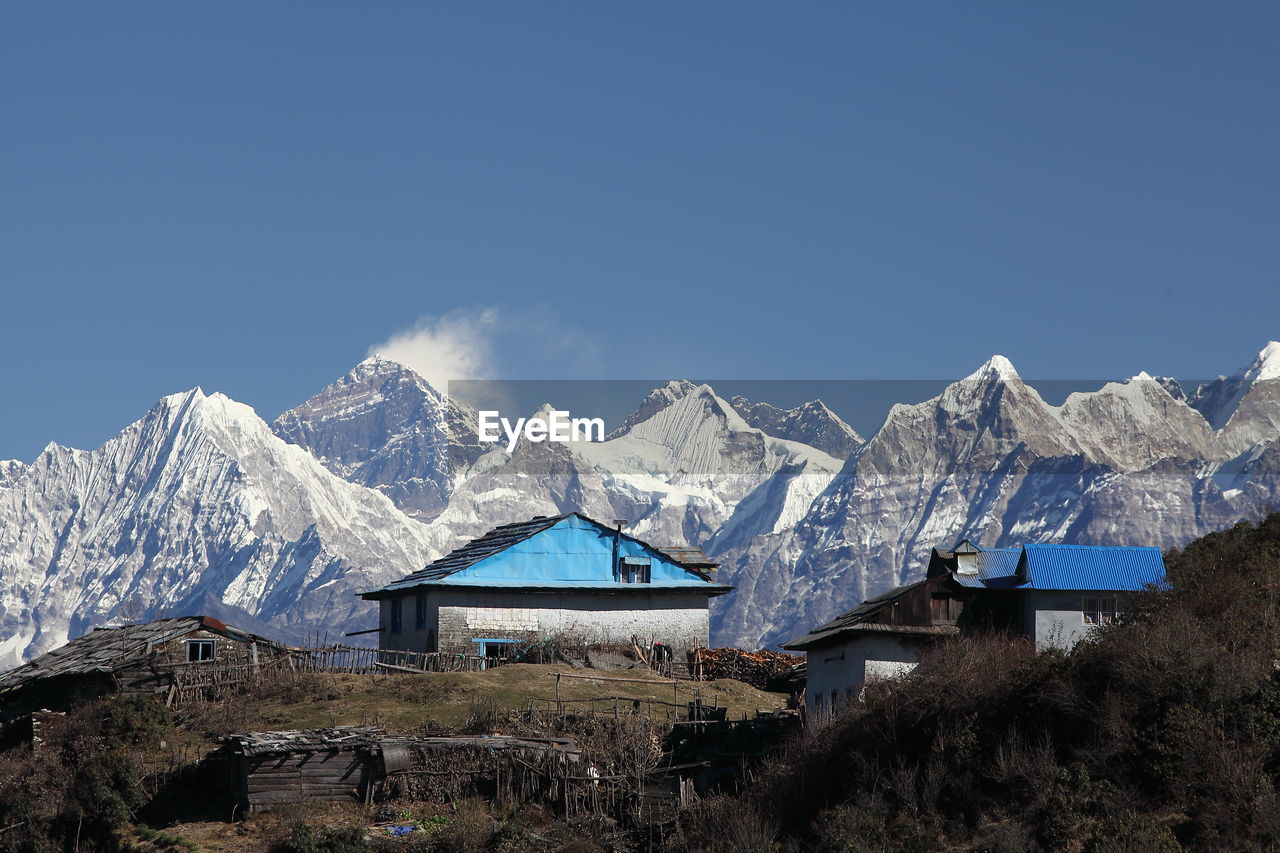 Cottages and snowcapped mountains against clear sky