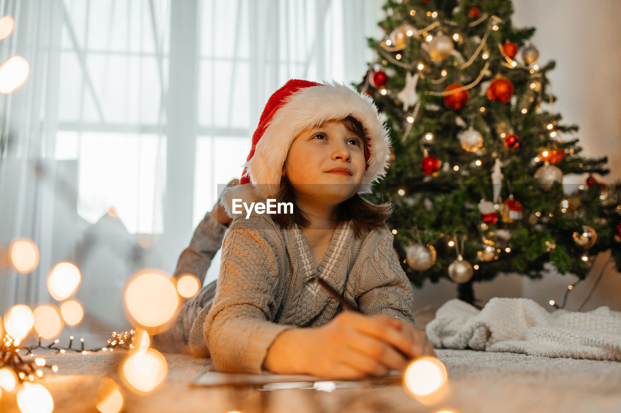 New year's and christmas. a teenage girl in a santa claus hat writes a letter to santa claus 