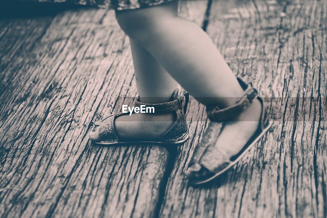 Close-up low section of kid walking on wooden surface