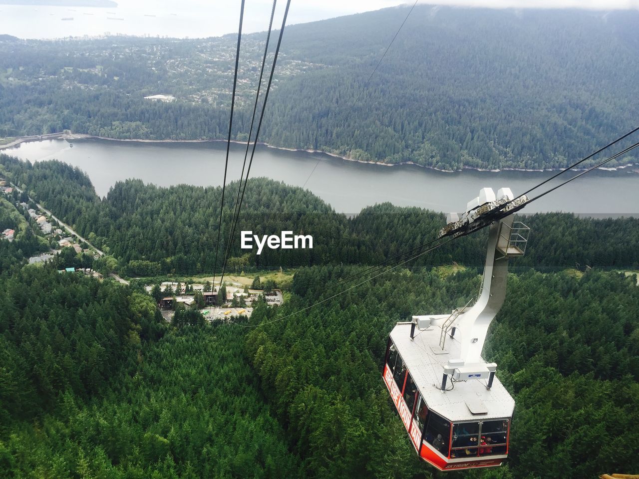 Ski lift over forest by river against mountains