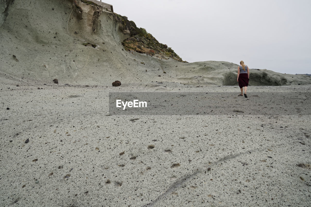 Woman walking on land against mountain