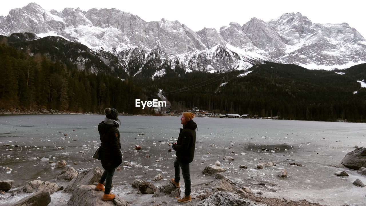 People standing by frozen lake