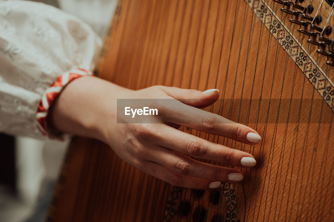 cropped hand of woman playing guitar