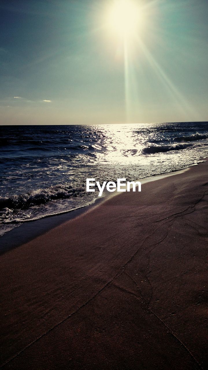 SCENIC VIEW OF BEACH AGAINST SKY AT SUNSET