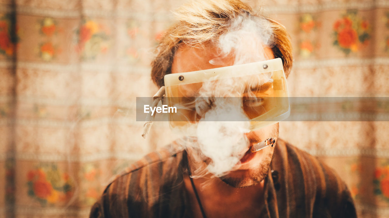 Man wearing protective eyeglasses while smoking cigarette