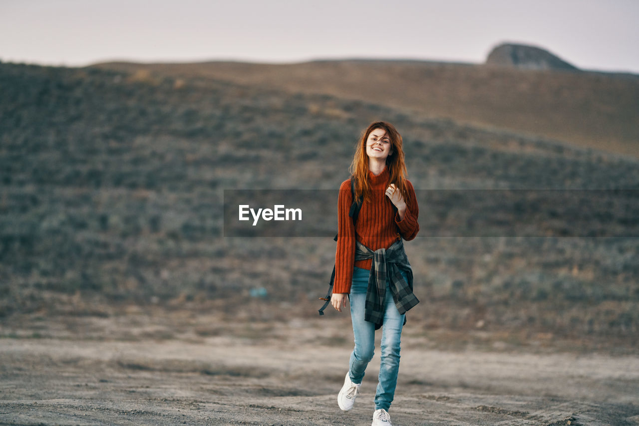 PORTRAIT OF YOUNG WOMAN STANDING ON GROUND