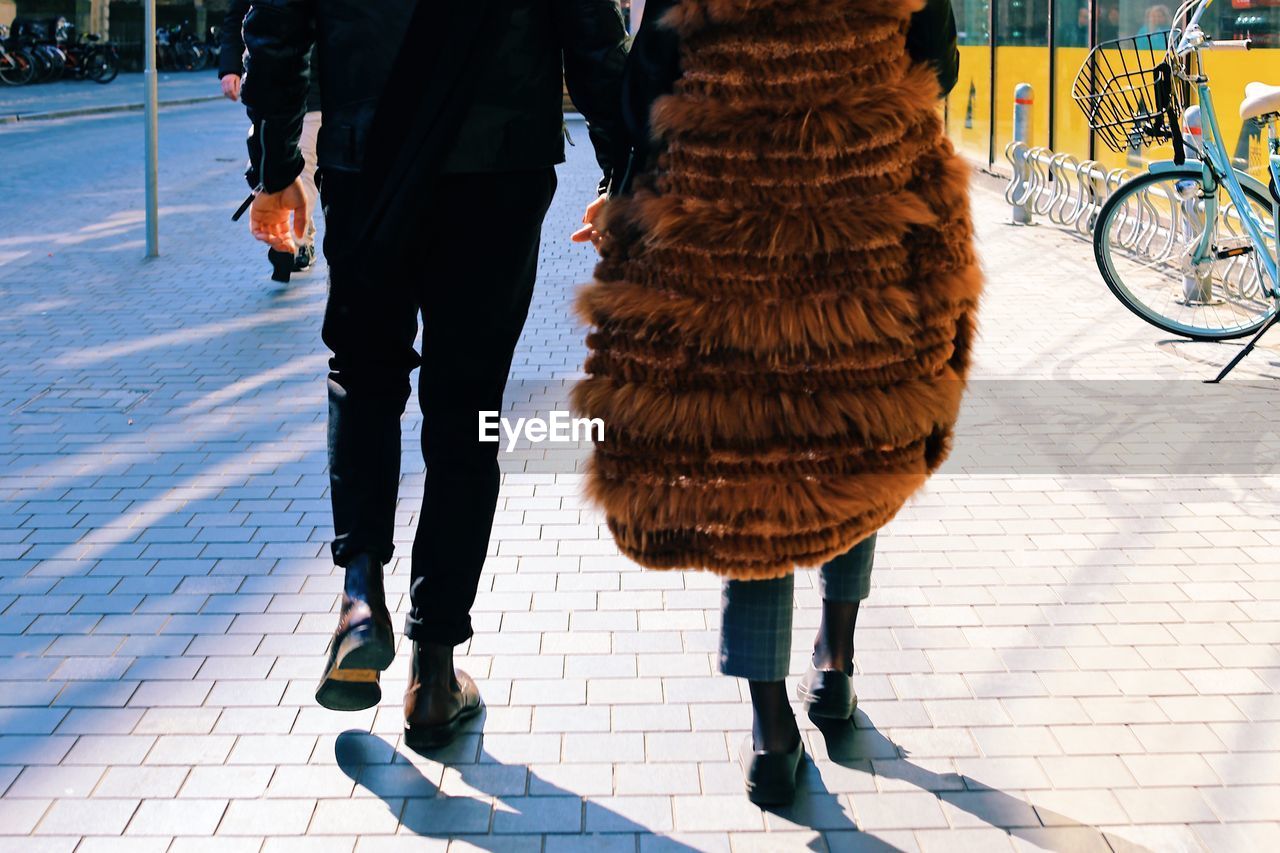 Low section of couple walking on street