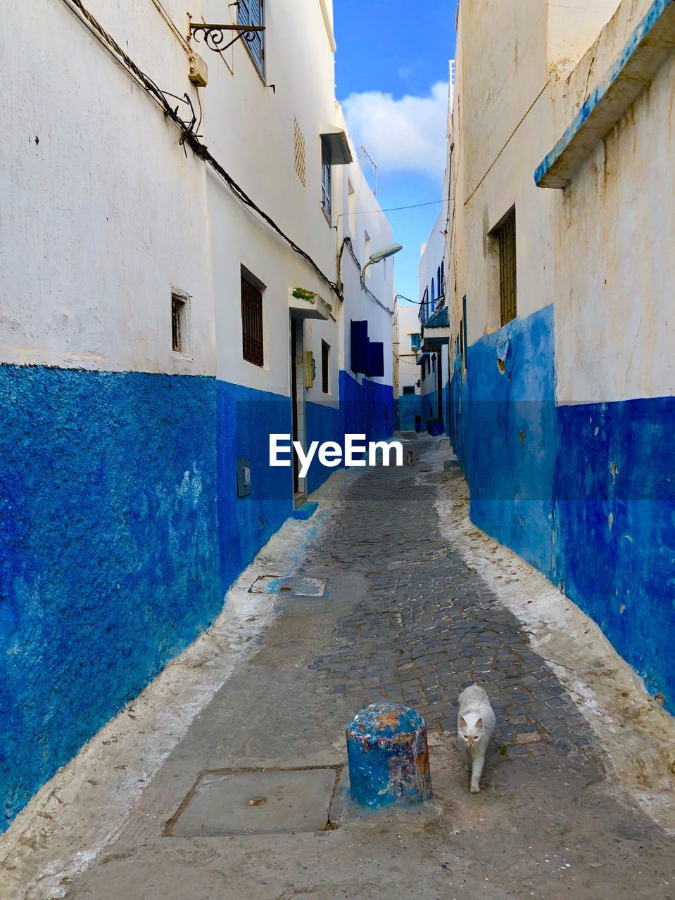 STREET AMIDST BUILDINGS AGAINST BLUE SKY