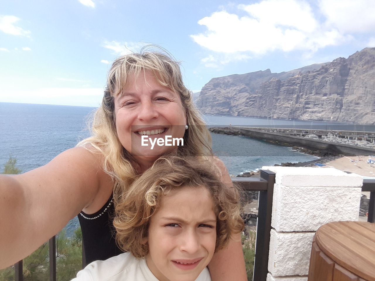 Portrait of happy mother with son standing against sea