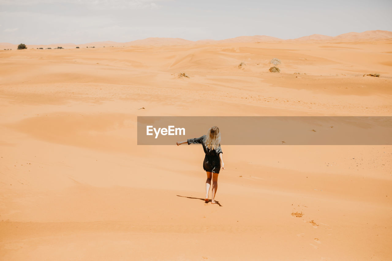 Woman walking on desert in sunny day