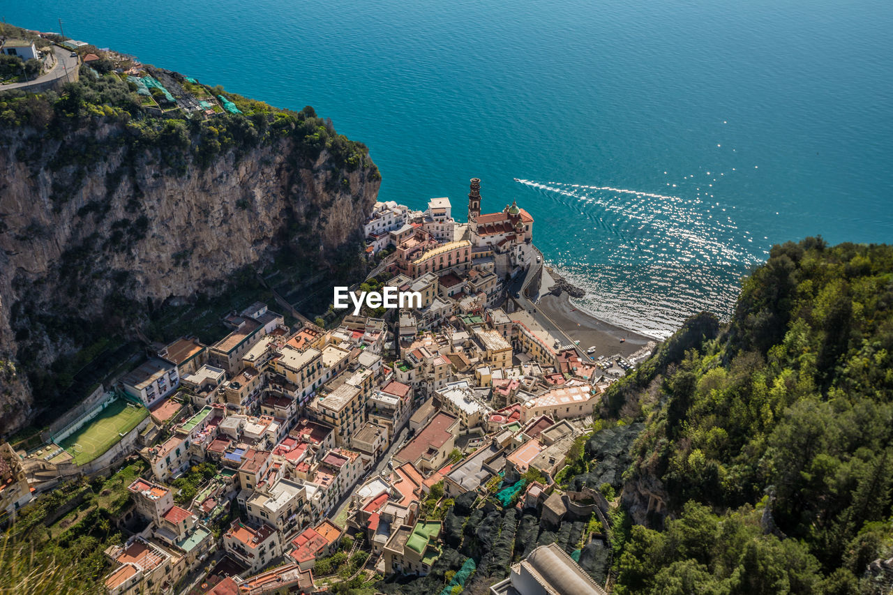 High angle view of houses on mountain by sea during sunny day