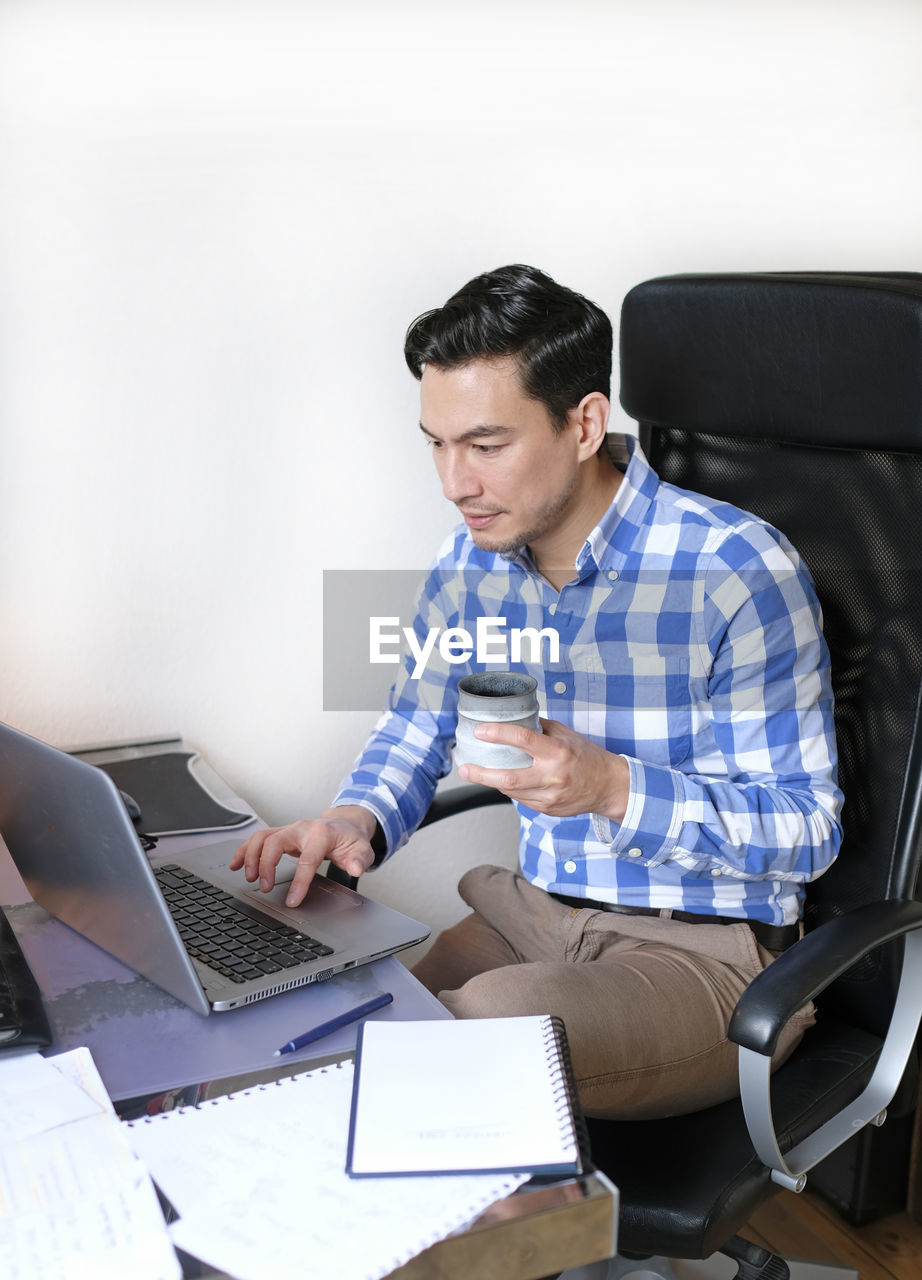 Man in casual outfit working from home with a laptop in the living room