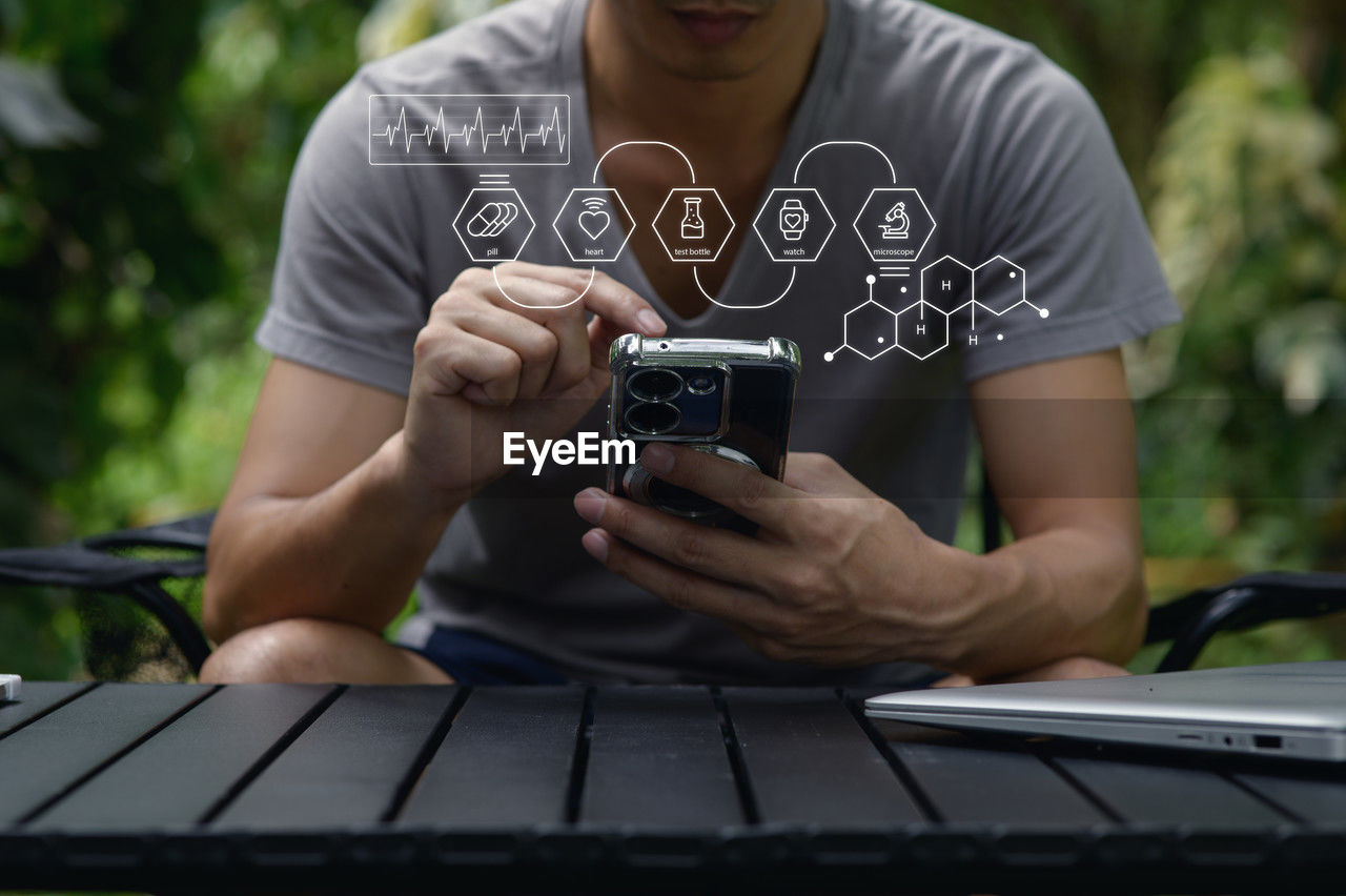 technology, one person, adult, wireless technology, front view, communication, casual clothing, day, lifestyles, holding, men, activity, leisure activity, young adult, sitting, outdoors, person, relaxation, nature