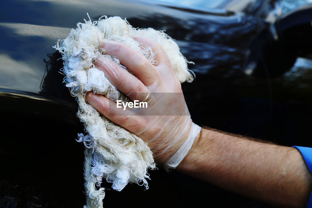Close-up of man hand cleaning car at garage