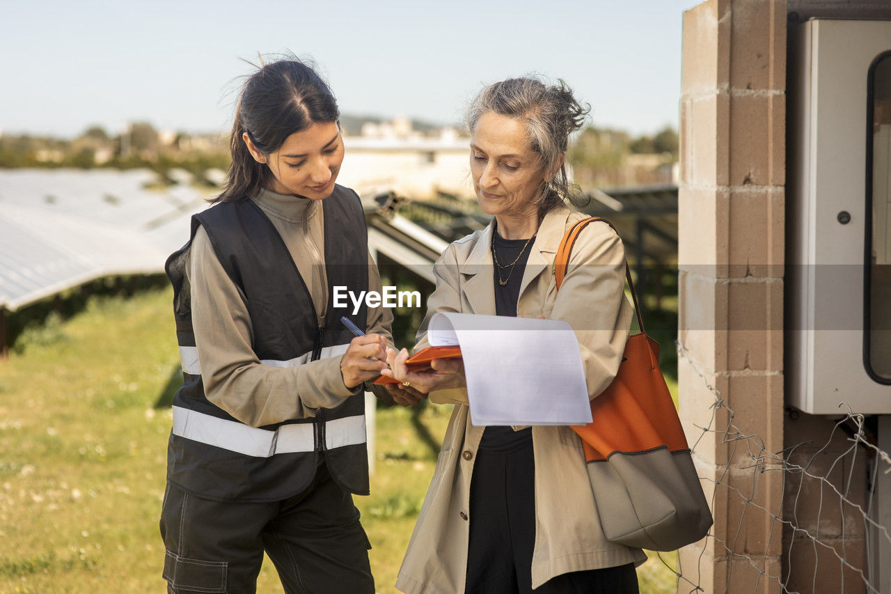 Female entrepreneur taking signature of engineer after visit at solar power station