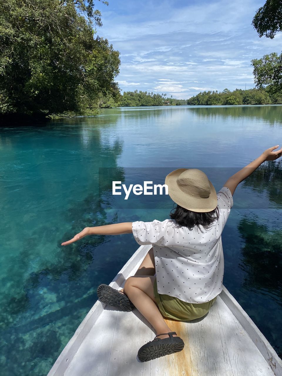 REAR VIEW OF WOMAN BY LAKE AGAINST TREES
