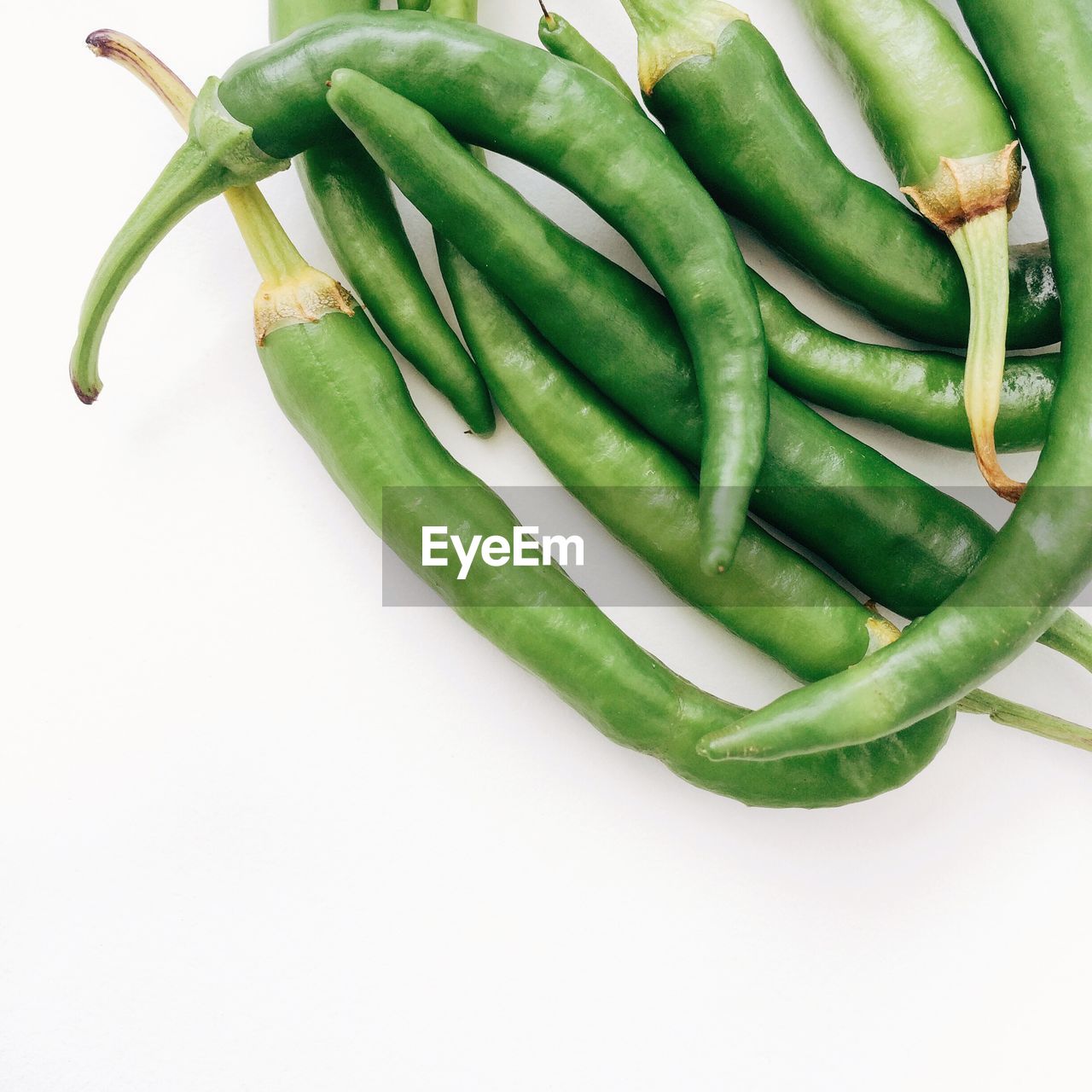 Close-up of fresh green chili peppers on white background