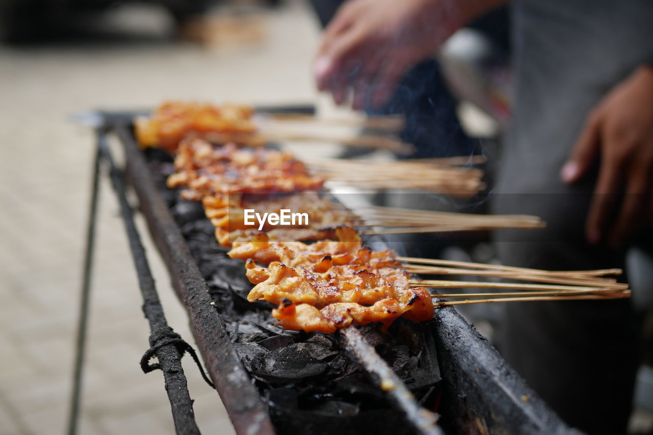 A process of grilling a few ribs of blurry chicken satay over noisy or grainy of black charcoal