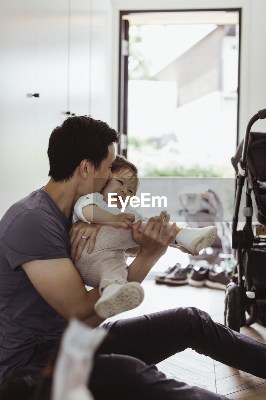 Father kissing baby son at home