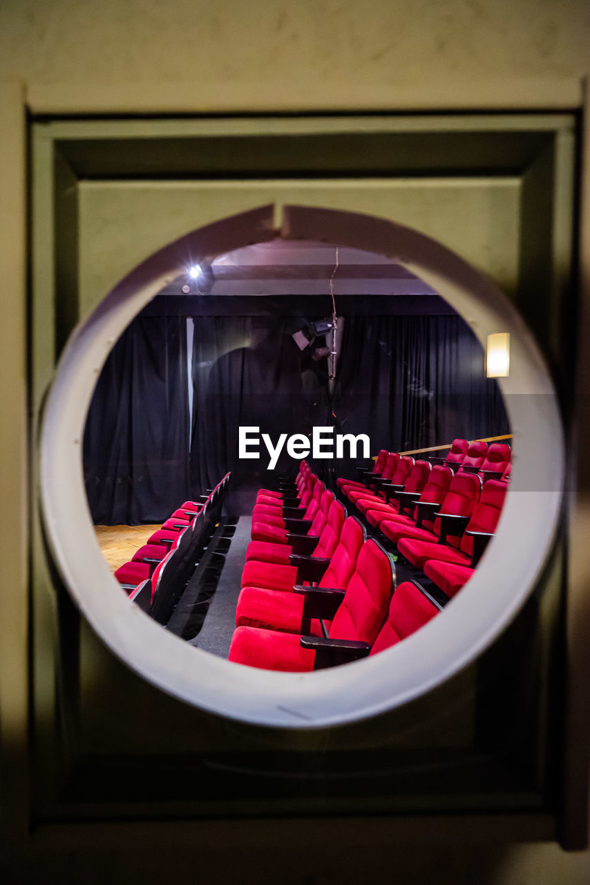 Porthole view into a cinema with red chairs