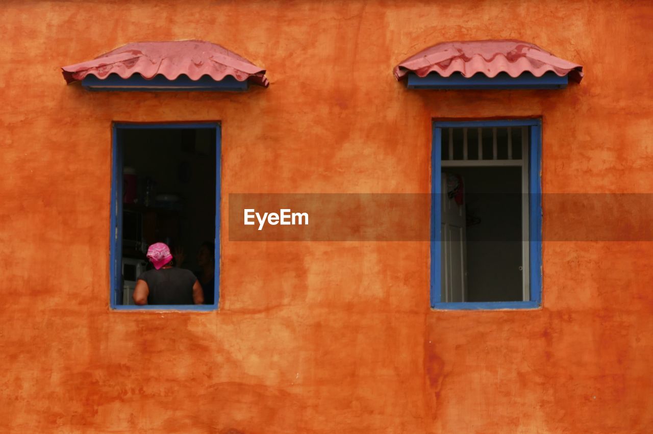 Rear view of person standing at window