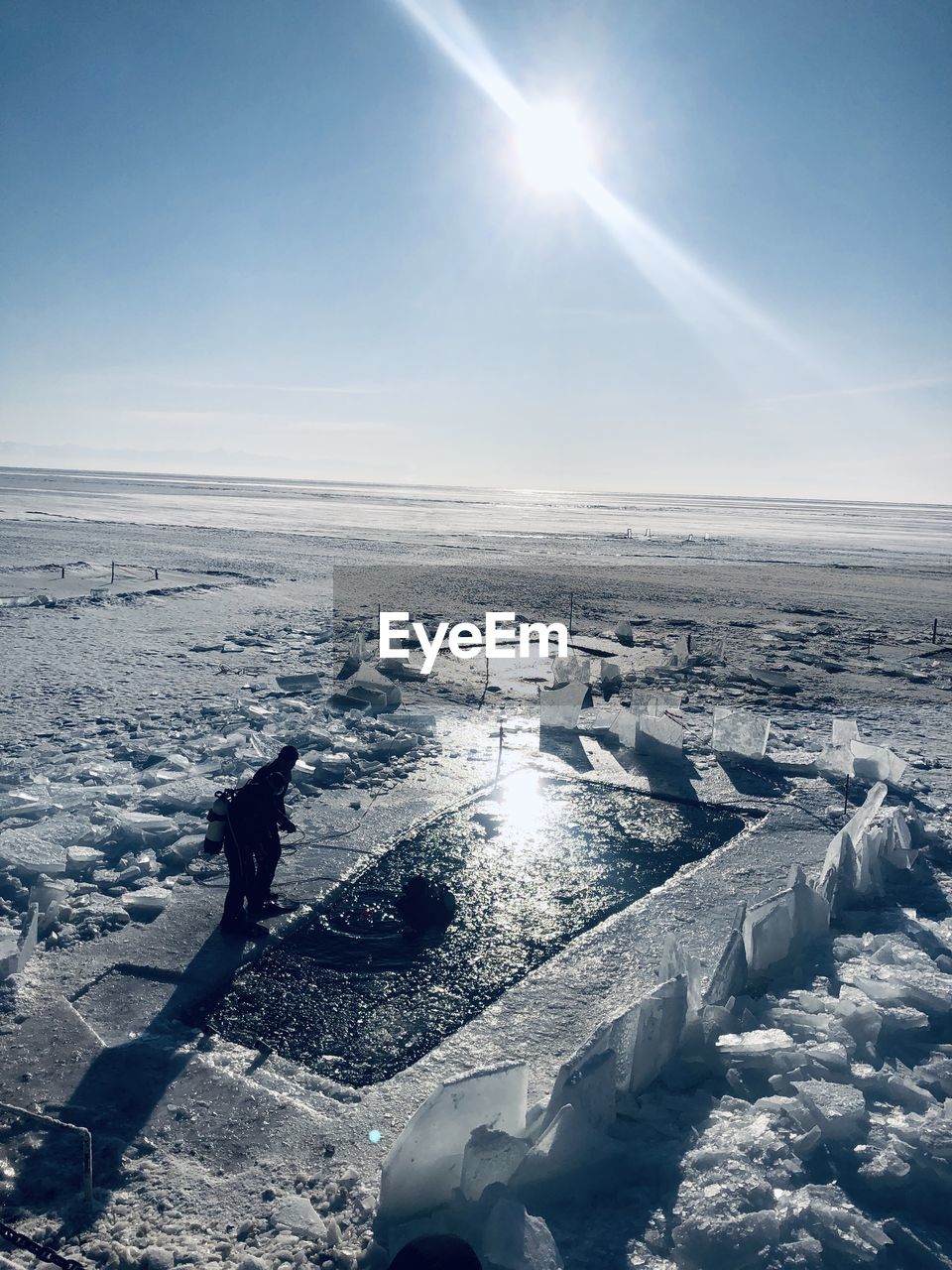 SCENIC VIEW OF FROZEN LAKE AGAINST BRIGHT SUN